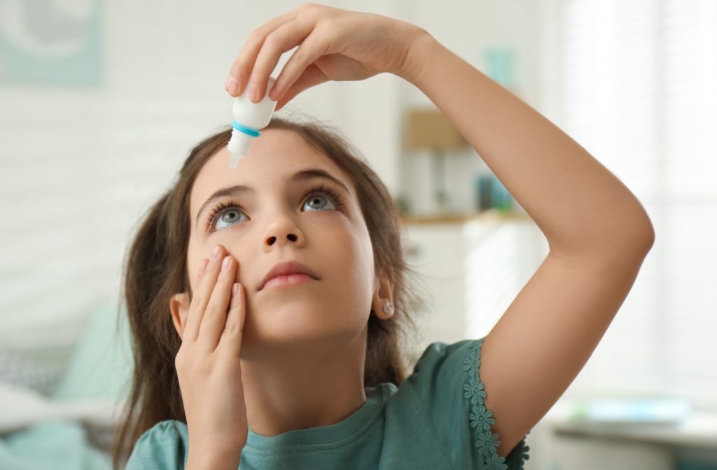 A girl applying atropine eye drops on her right eye.